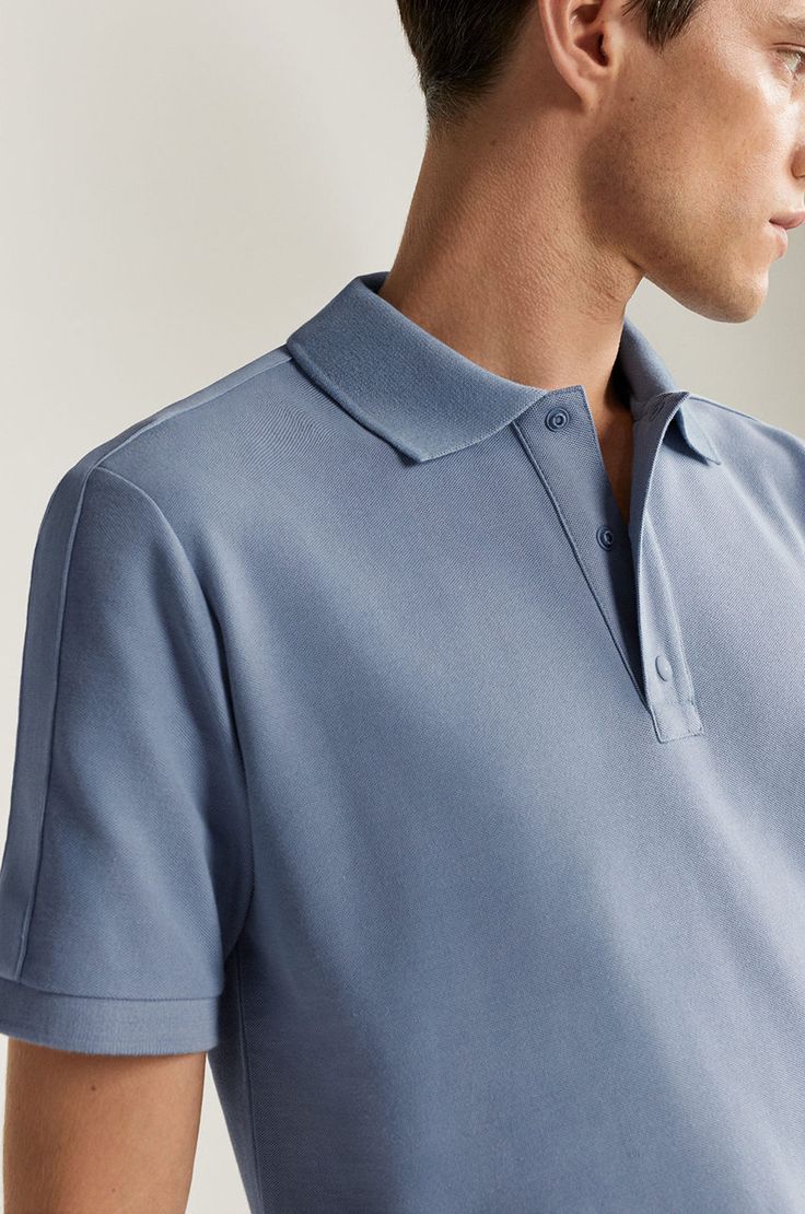 Close-up of a man wearing a light blue polo shirt, displaying the collar and button details.