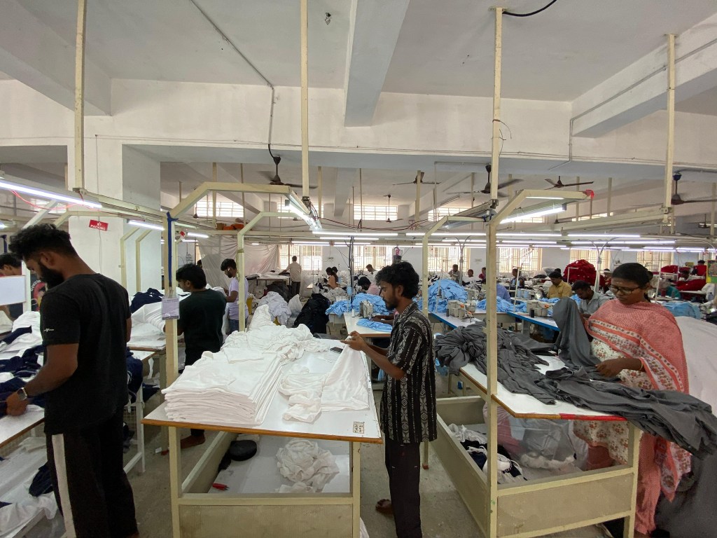 Workers in a textile factory organizing and folding clothes on tables in a well-lit manufacturing space.