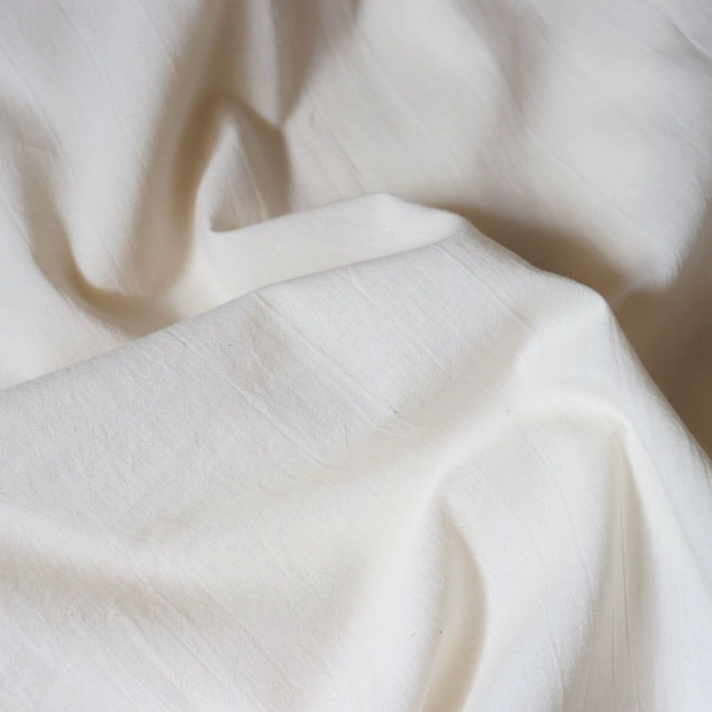 Close-up view of soft, crumpled white fabric showcasing its texture.